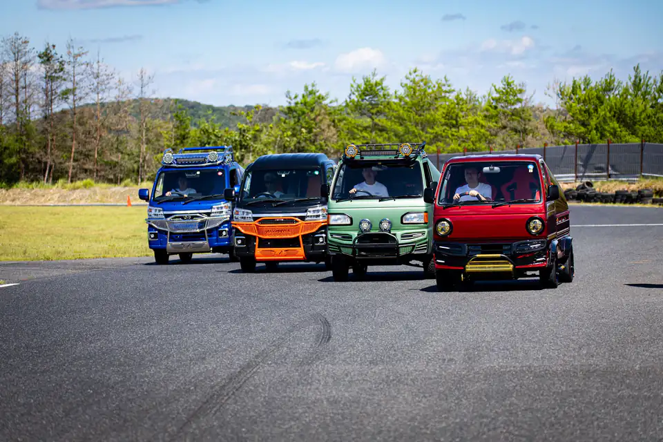 Four customized Kei Trucks and Kei Vans lined up side by side at a Japanese mini truck meet