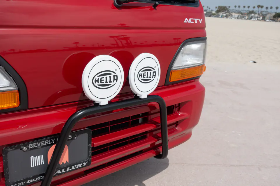 Round driving lights mounted on a black bull bar on a red Honda Acty Kei Truck