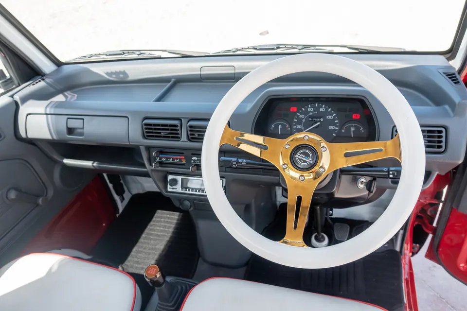 Custom white and gold steering wheel and two-tone seat covers inside a Honda Acty
