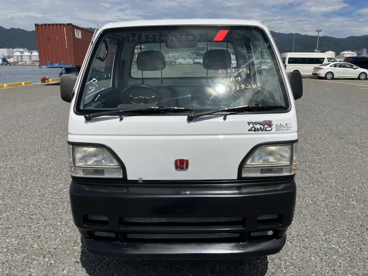 Front view of a white Honda Acty HA4 Kei Truck at a port in Japan