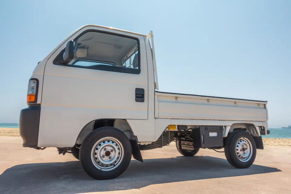 Side profile of a white Honda Acty Kei Truck showing the short wheelbase and drop-side bed
