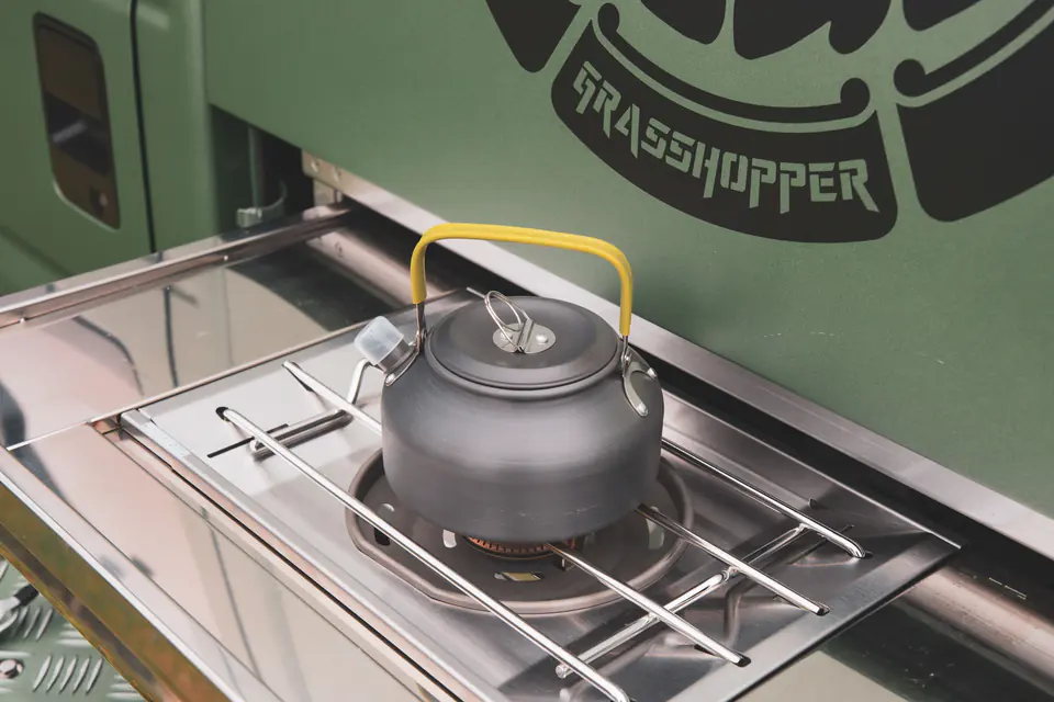 Slide-out camp kitchen with a stove and kettle built into a Kei Truck camper