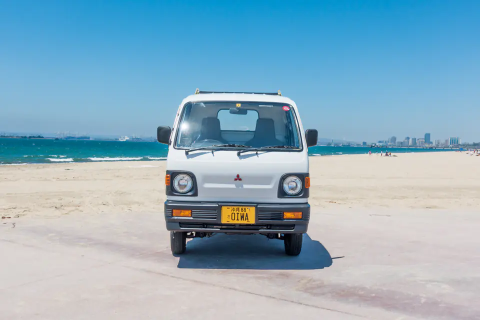 Front view of a 1990s Mitsubishi Minicab Kei Truck with round headlights