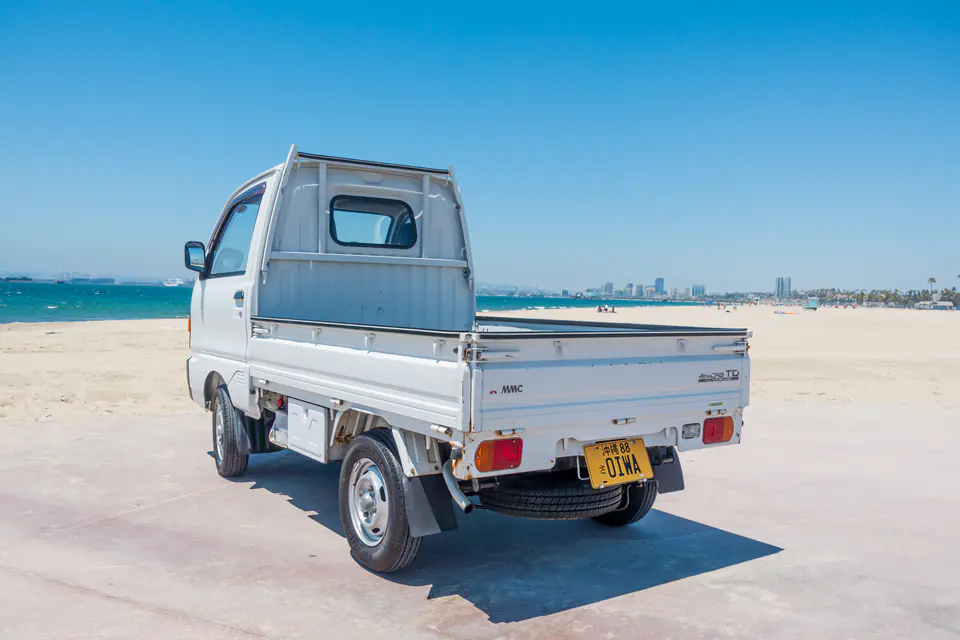 Rear three-quarter view of a Mitsubishi Minicab Kei Truck with a drop-side bed