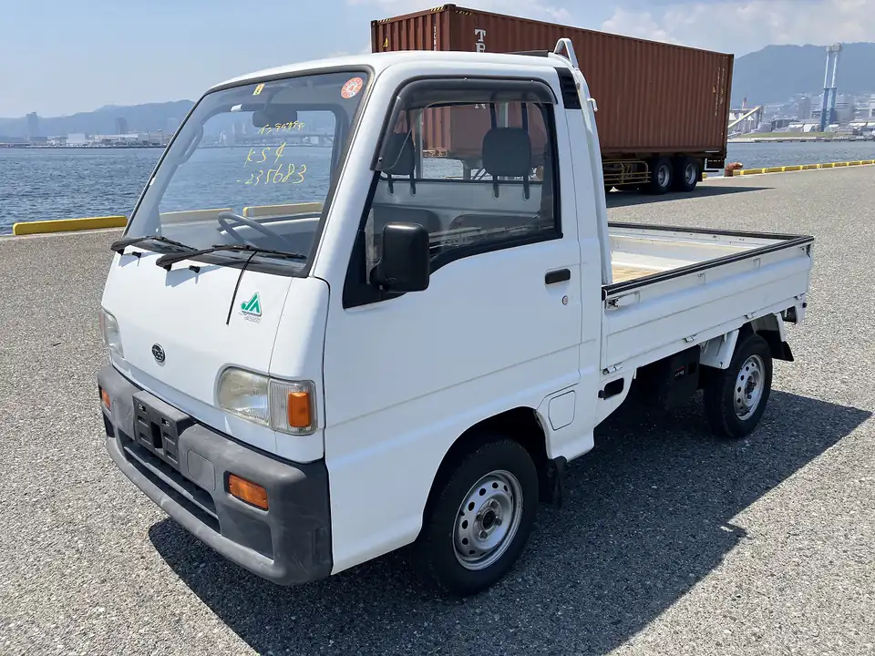 White Subaru Sambar KS4 Kei Truck at a Japanese port with shipping containers behind it