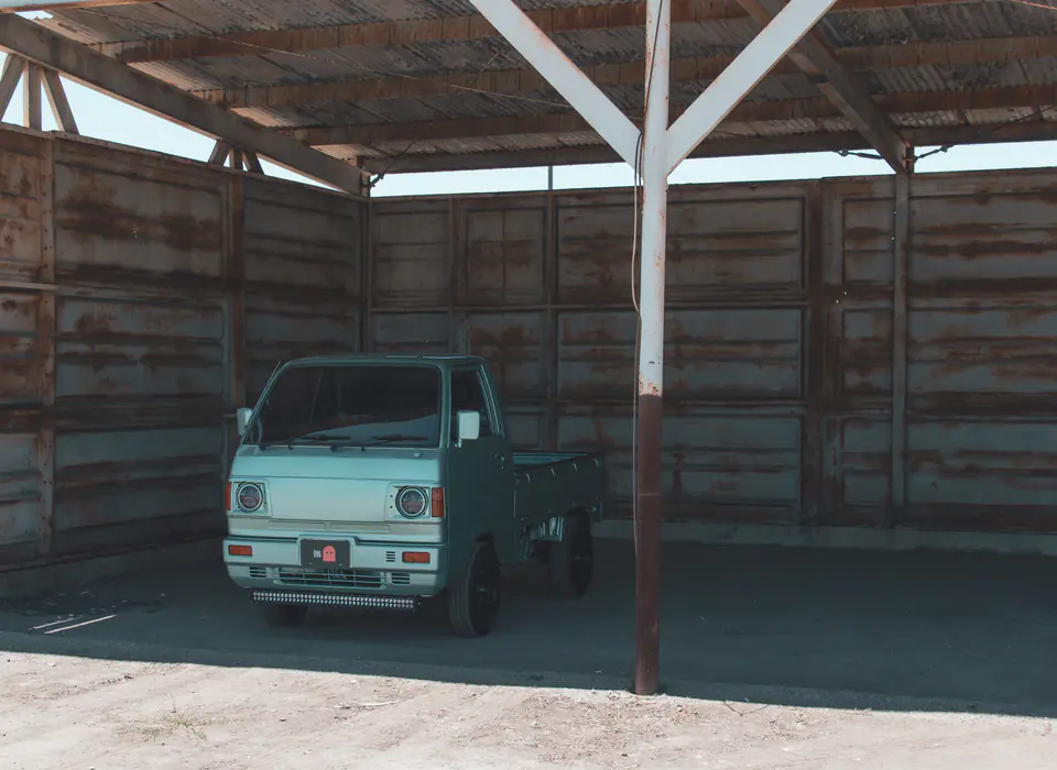 Mint green vintage Honda Acty Kei Truck parked inside a weathered wooden shed