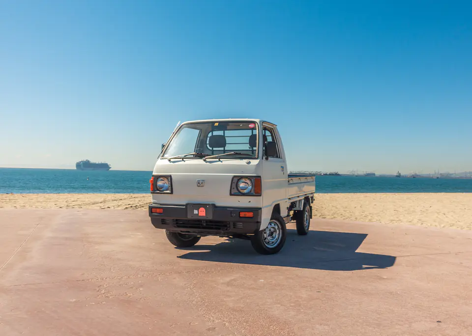 White Honda Acty Kei Truck parked on the sand near the ocean